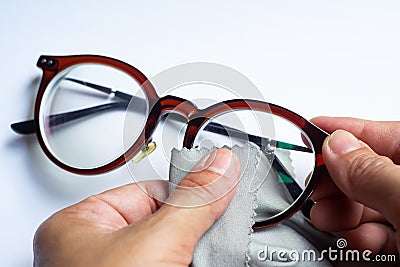 Woman hands cleaning shortsighted or nearsighted eyeglasses by microfibre cleaning cloths, On white background, Optical concept Stock Photo