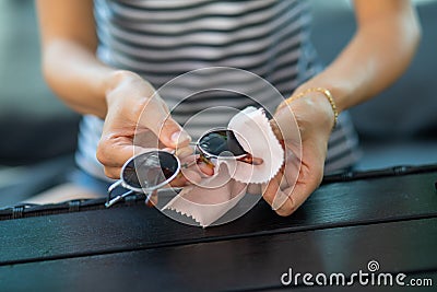 Woman hands cleaning and wiping sun glasses with micro fiber wipe Stock Photo