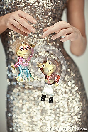 Woman hands close up holding christmas decoration baubles, little dancing frogs Stock Photo