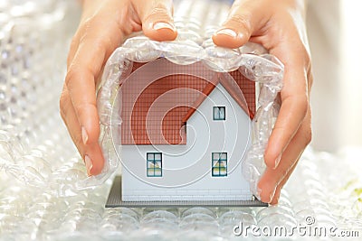 Woman hands covering a model house with bubble wrap- house protection or insurance concept Stock Photo