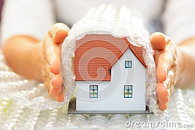 Woman hands covering a model house with bubble wrap- house protection or insurance concept Stock Photo