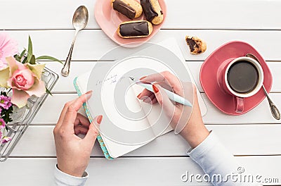 Woman hands drawing or writing with ink pen in open notebook on white wooden table. Stock Photo