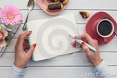 Woman hands drawing or writing with ink pen in open notebook on white wooden table. Stock Photo