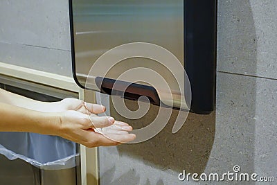 Woman hands dries wet hand in modern vertical hand dryer in public restroom Stock Photo