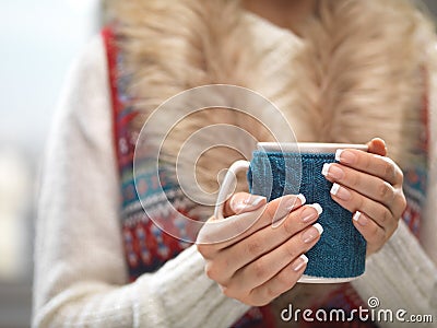 Woman hands with elegant french manicure nails design holding a cozy knitted mug. Winter and Christmas time concept. Stock Photo