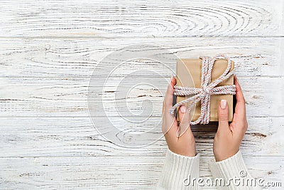 Woman hands give wrapped valentine or other holiday handmade present in paper with pink ribbon. Present box, decoration of gift on Stock Photo