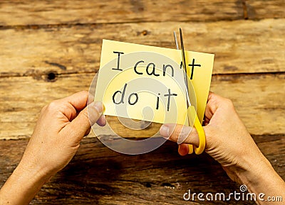 Woman hands using scissors to remove letter T from written text I can`t do it to read I can Stock Photo