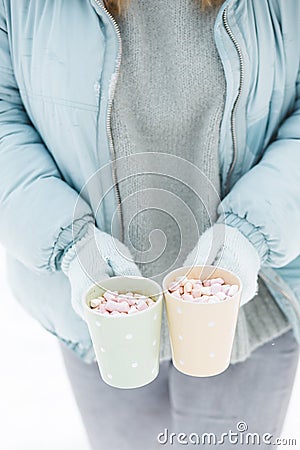 Woman Hands Holding Cup of Hot Chocolate with Marshmallow candies. Knitted mittens and Warm cocoa drink Stock Photo