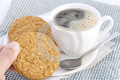 Woman hands holding homemade shortbread cookies made of oatmeal stacked in plate with hot coffee cup on cloth on white table Stock Photo