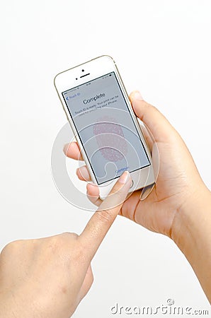 Woman hands holding and touching an Apple iPhone 5s color gold showing fingerprint scan interface. Editorial Stock Photo