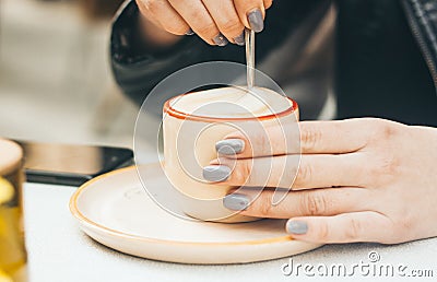 Woman hands with manicure holding a cup with capuccino outdoors Stock Photo