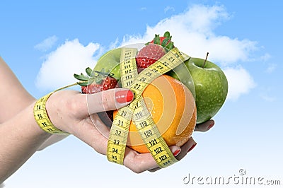 Woman hands with mix of fruit bond wrist wrapped with measure tape in dieting Stock Photo