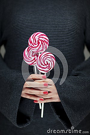 Woman hands with perfect nail polish holding some pink and white lollypops Stock Photo