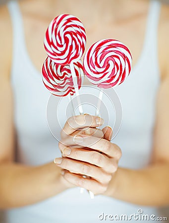 Woman hands with perfect nail polish holding some pink and white lollypops Stock Photo