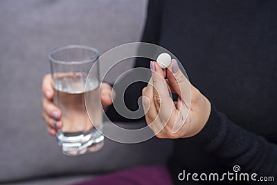 Woman hands with pills and glass of water. A young woman is taking medication, feeling bad. Healthcare concept Stock Photo