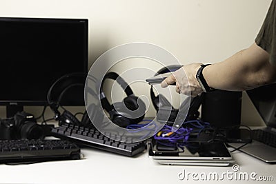 Woman hands put mobile cell phones on pile of old used computers and electronic devices for recycling on white table Stock Photo