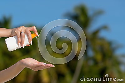 Woman hands putting sunscreen from a suncream bottle Stock Photo