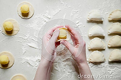 Woman Hands Sculpts Dumplings with Potatoes on White Background. Traditional Ukrainian Food Stock Photo