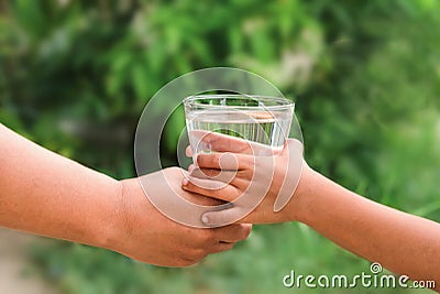 Woman hands to drink water with children hands green leaf background Stock Photo