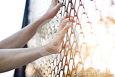 Woman hands touching a metal fence wire Stock Photo