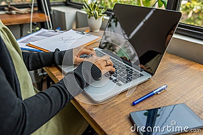 Woman hands typing laptop next to cellphone on wood table Stock Photo