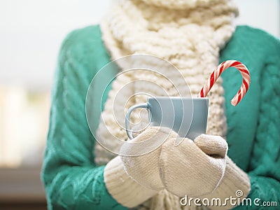 Woman hands in white woolen mittens holding a cozy cup with hot cocoa, tea or coffee. Winter and Christmas time concept. Stock Photo