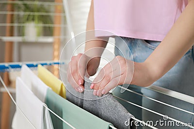 Woman hanging different apparel on clothes airer indoors, closeup Stock Photo