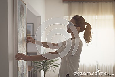 Woman hanging a painting at home Stock Photo