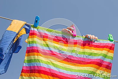 Woman hanging towel to dry on clothesline after laundry in the sun on blur nature background, good weather at summer or spring sea Stock Photo