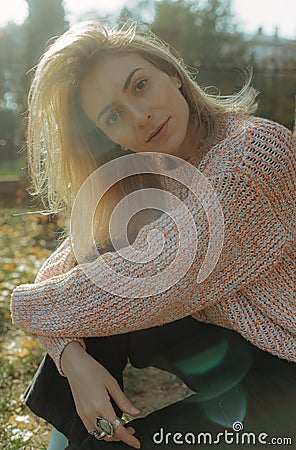 Woman with happy smile on face in park, rejoices. Girl in casual demi-season clothes on blurred background of city park Stock Photo