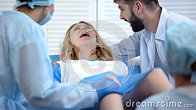 Woman hardly pushing to give child birth, natural labor and delivery, hospital Stock Photo
