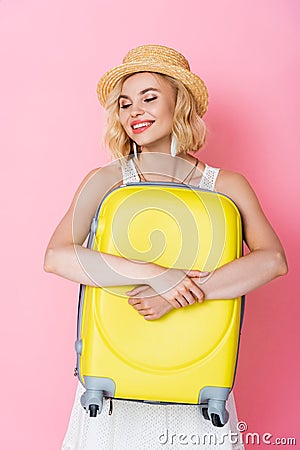 Woman in hat embracing yellow luggage Stock Photo