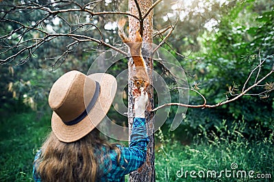 Woman in Hat feeding squirrel in forest Stock Photo