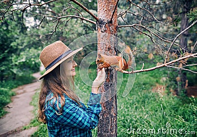 Woman in Hat feeding squirrel in forest Stock Photo