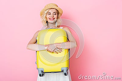 Woman in hat hugging yellow luggage Stock Photo