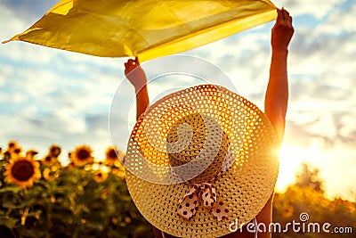 Woman in hat relaxing in blooming sunflower field raised arms with scarf and having fun. Free and happy. Summer vacation Stock Photo