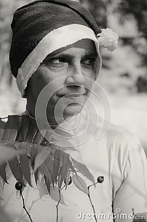 A woman in a hat of Santaclaus with a sly evil face among the autumn foliage as a harbinger of the coming winter. Stock Photo