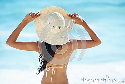Woman, hat and travel to beach or sea, nature and relaxing by ocean for peace on vacation. Female person, outdoors and Stock Photo