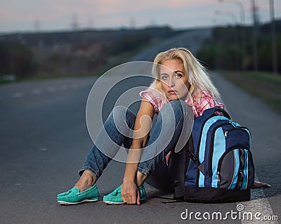 Woman with haversack sitting on the road Stock Photo