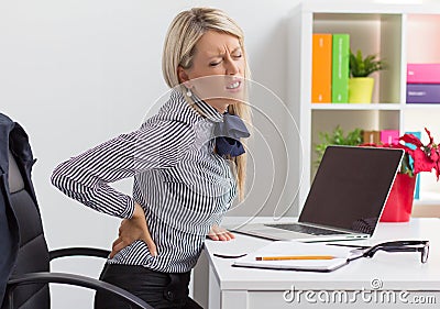 Woman having back pain while sitting at desk in office Stock Photo