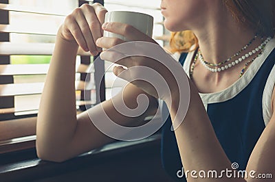 Woman having coffee by the window in a diner Stock Photo