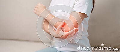 Woman having elbow ache during sitting on couch at home, muscle pain due to lateral epicondylitis or tennis elbow. injury, Health Stock Photo