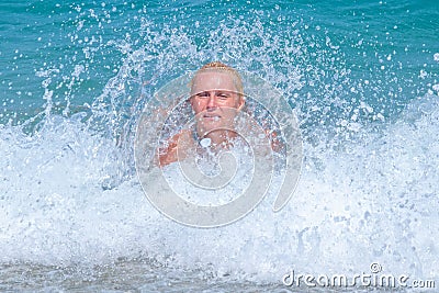 A woman having fun in the waves of the sea which are splashing her. The beautiful woman mother of three in bikini Stock Photo