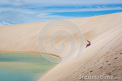 Woman having a good time, rolling down a huge sand dune in a amazing scenario, natural pool lagoon in the bottom. North of Brasil, Editorial Stock Photo