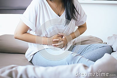 Woman having painful stomachache standing in the bedroom,Female suffering from abdominal pain Stock Photo