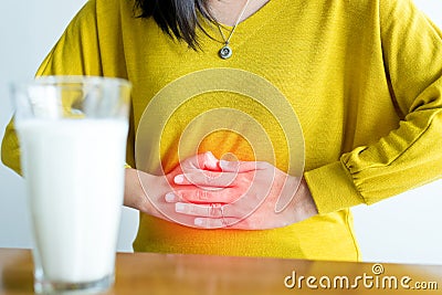 Woman having a stomach pain and a glass of milk,Allergy dairy intolerant,Lactose intolerance concept Stock Photo