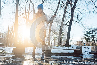 Woman having to step into a puddle of water and thawing snow Stock Photo