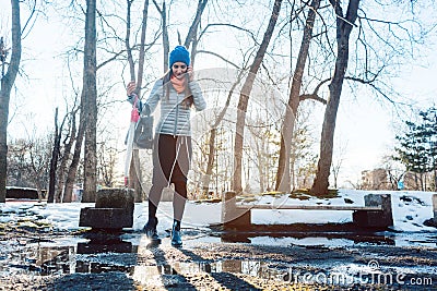 Woman having to step into a puddle of water and thawing snow Stock Photo