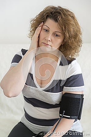 Woman with headache measures a blood pressure Stock Photo