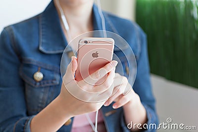 Woman with headphones holding in the hand iPhone6S Rose Gold Editorial Stock Photo